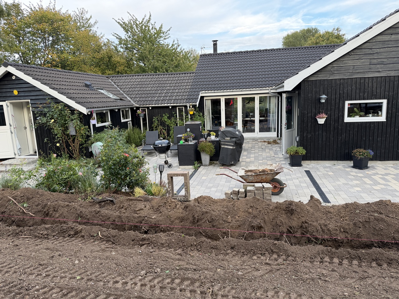 Ryddet jord og en rende foran sommerhusets gårdhave efter hækfjernelse i Gilleleje.
