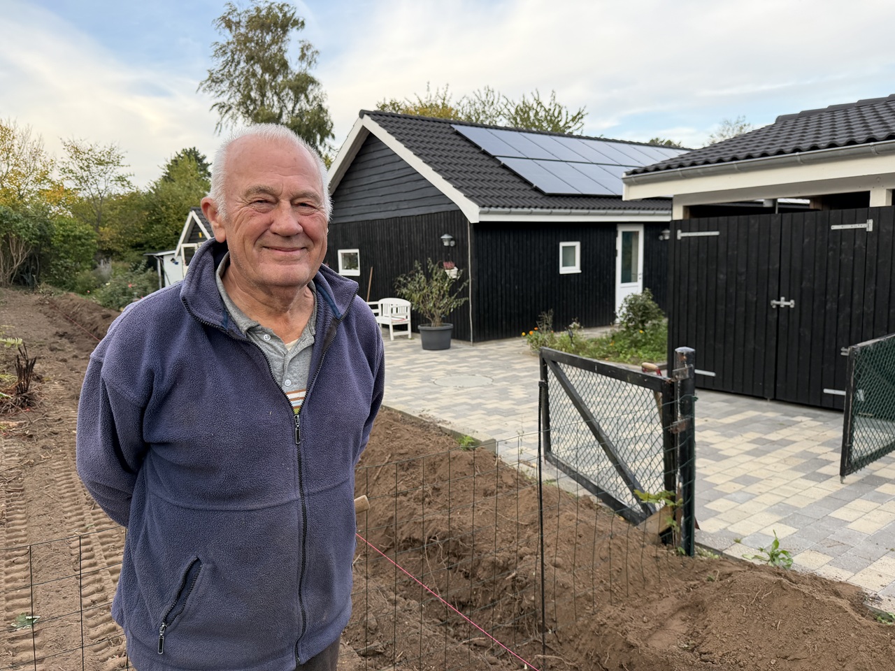Smilende kunde foran sommerhuset og det ryddede område efter hækfjernelse i Gilleleje.